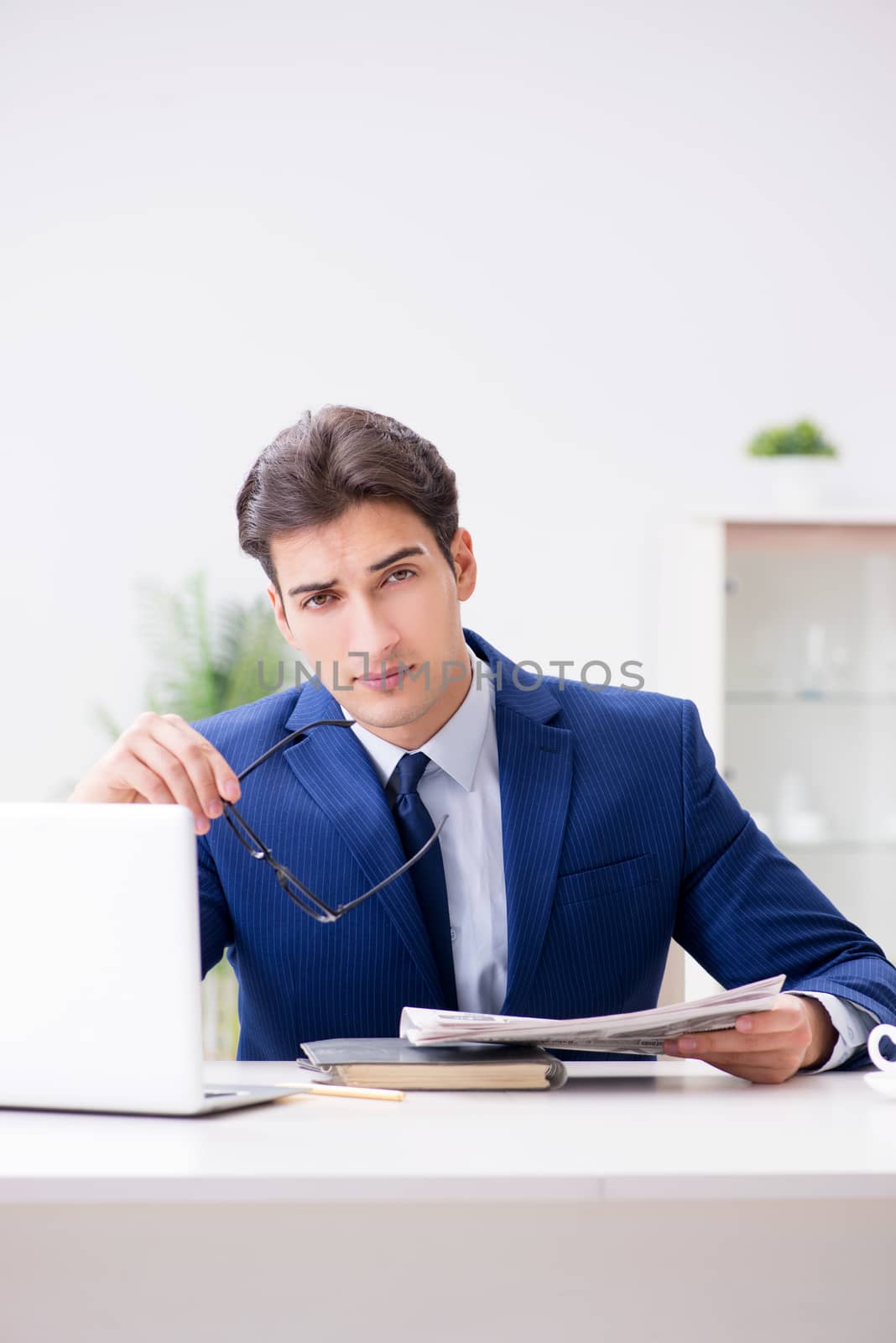 Young handsome businessman employee working in office at desk