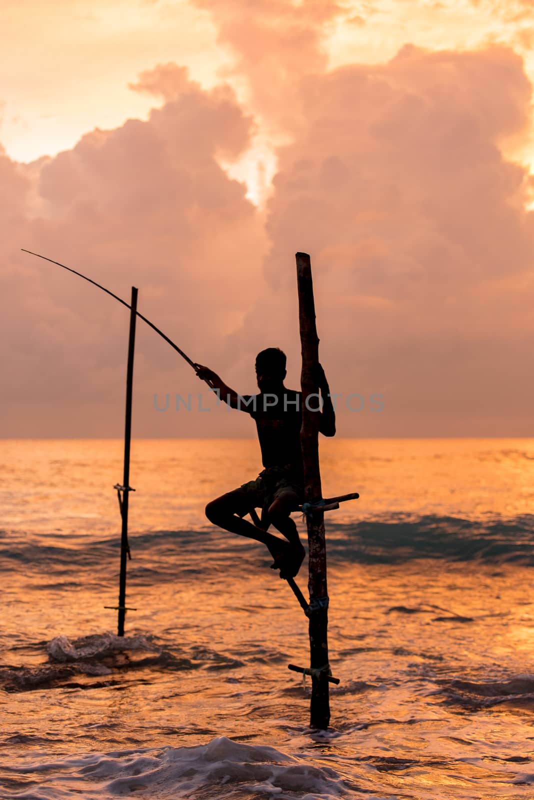 Silhouettes of the traditional Sri Lankan stilt fishermen on a stormy in Koggala, Sri Lanka. Stilt fishing is a method of fishing unique to the island country of Sri Lanka