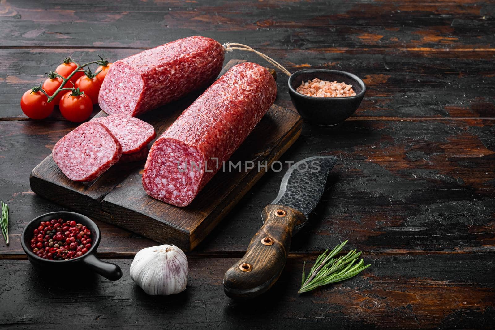 Salami with herbs and spices set, on old dark wooden table background, with copy space for text