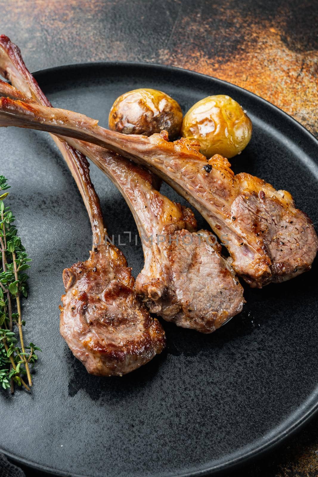 Grilled Lamb Steak with orange, garlic and carrot set, on plate, on old dark rustic background