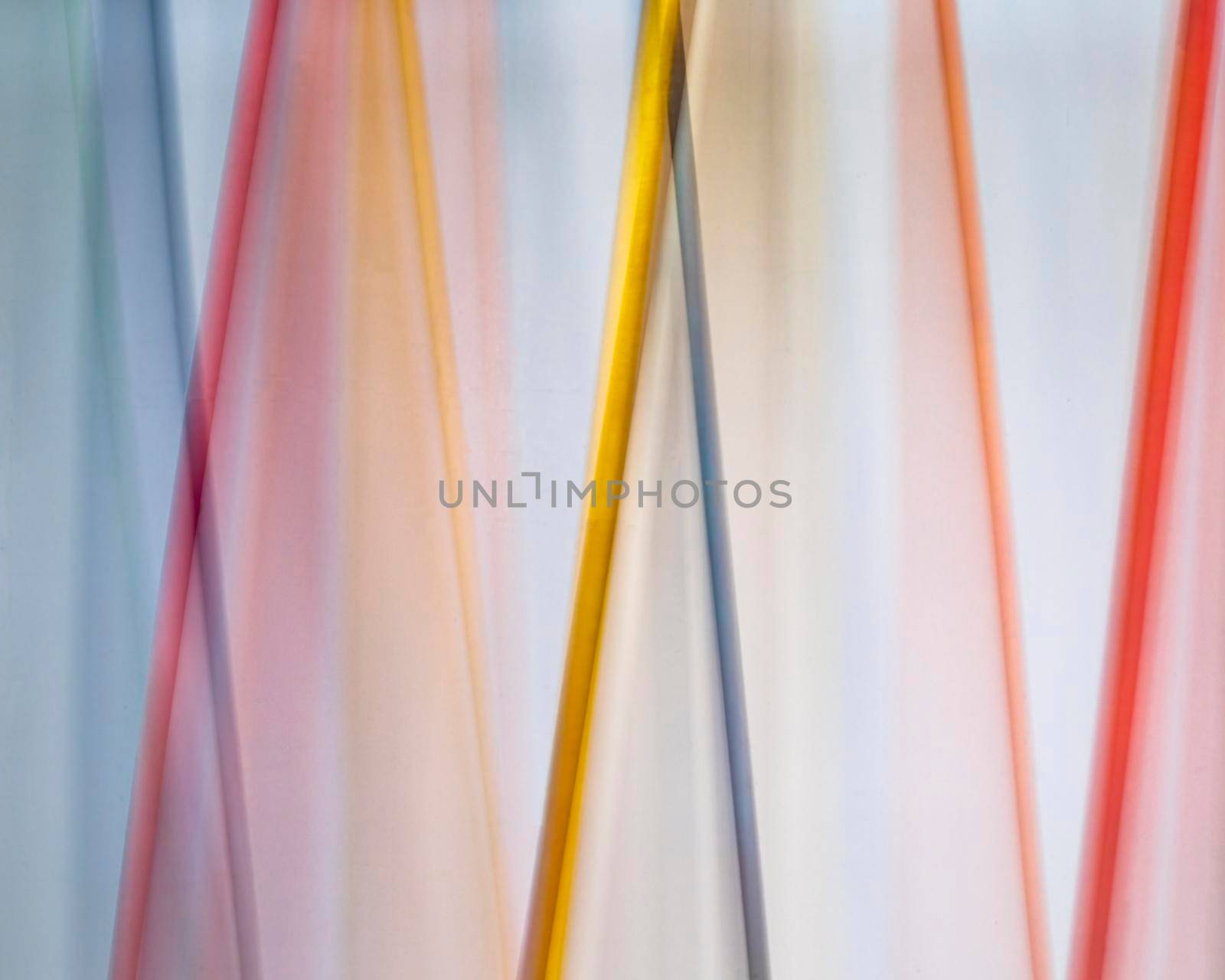Colored dowels swing against a white background in a time lapse photo.