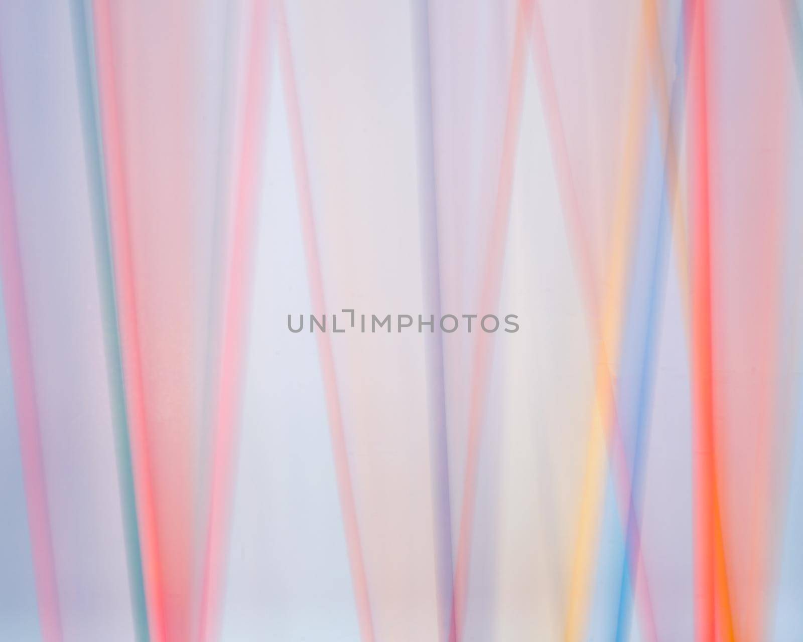 Colored dowels blurred against a white background in a time lapse photo.
