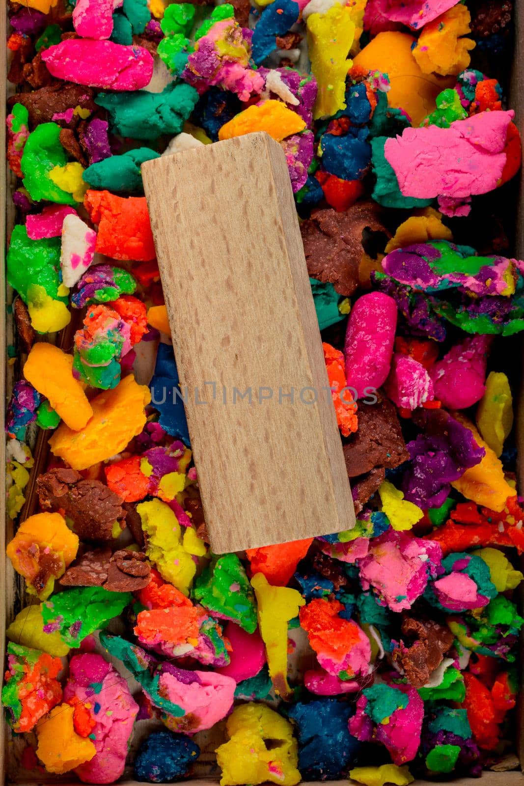 Piece of wood on colorful play dough in smal pieces