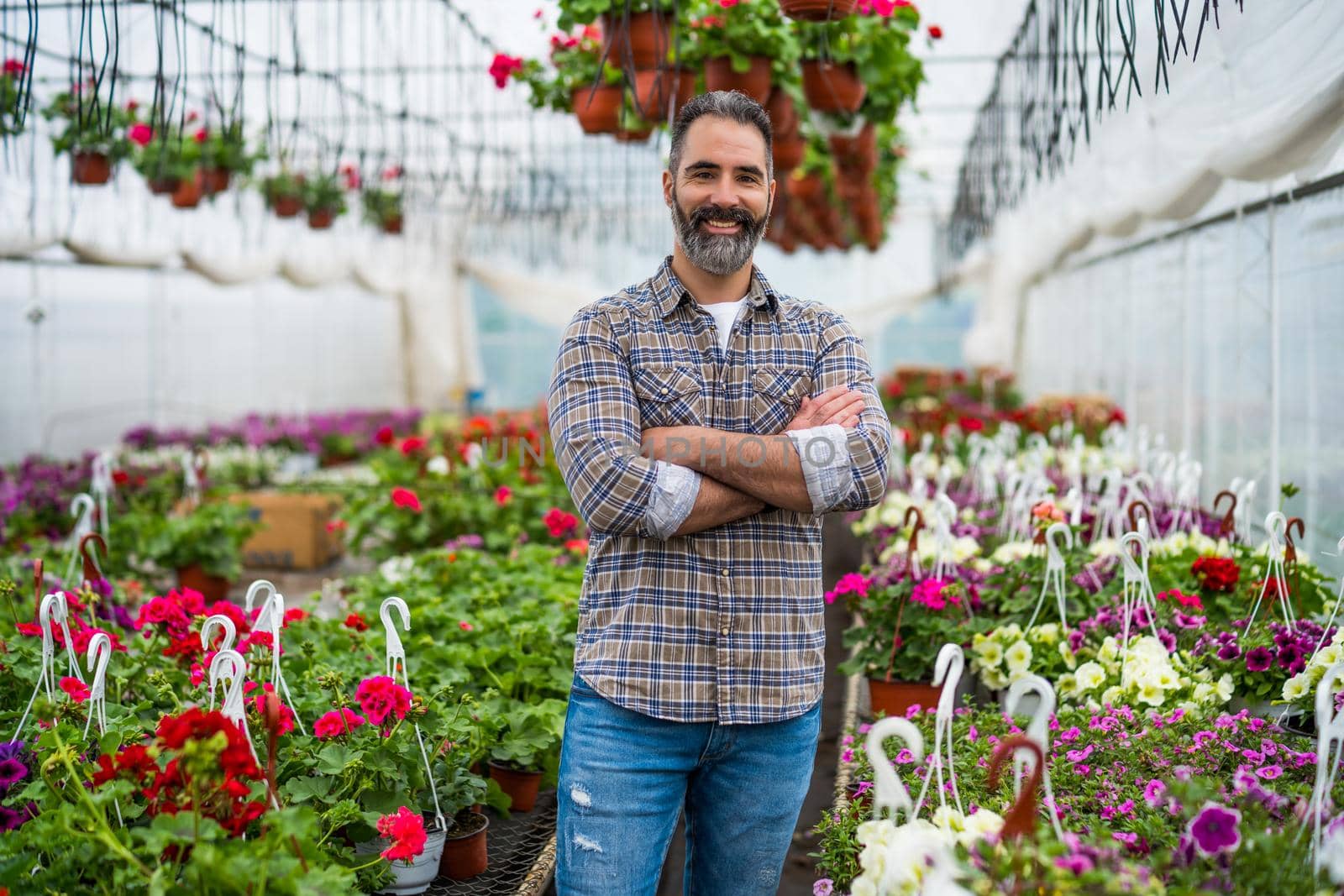 Adult man is owning small business greenhouse store.