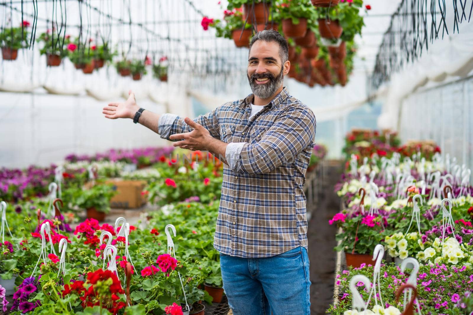 Adult man is owning small business greenhouse store.