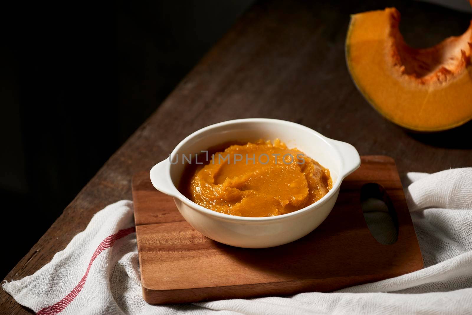 Pumpkin puree in a bowl on wooden background by makidotvn