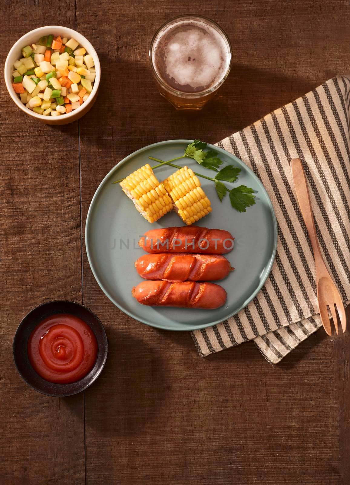 Home grilled sausages on a dark plate, a meat dish on a dark wooden background, hot sausages with spices and salt in a home kitchen, copy space, rustic style, art