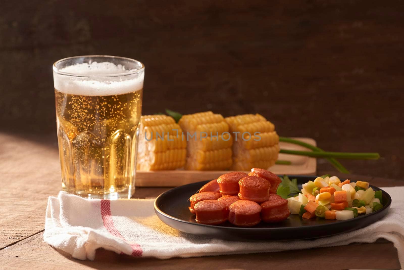 Grilled sausages with glass of beer on wooden table with copy space.
