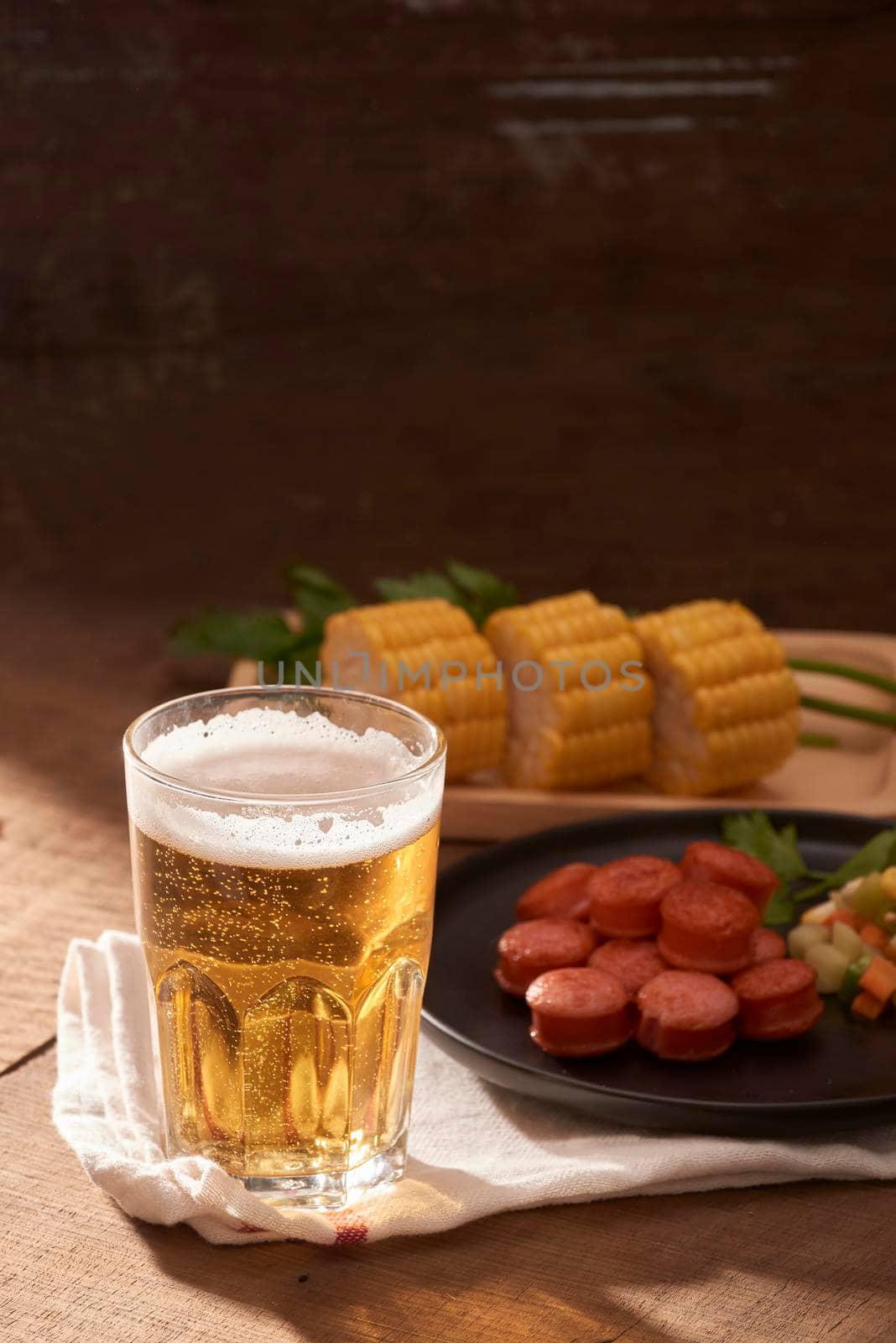 Grilled sausages with glass of beer on wooden table with copy space.