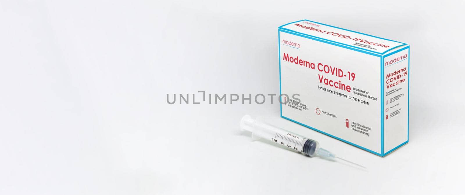 Cambridge, MA, USA, february 5th 2021: A syringe next to the ModeRNa Covid-19 vaccine box isolated on a white background. Health and prevention.