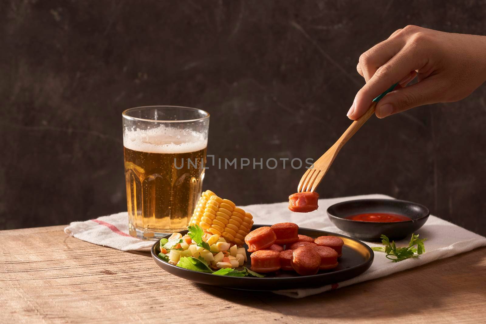 Man eating sliced sausages with salad and having wheat beer