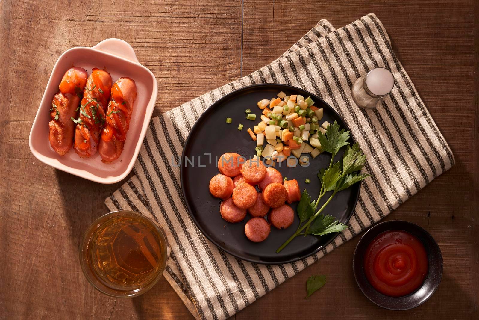 Glass of delicious beer with grilled sausages on wooden table