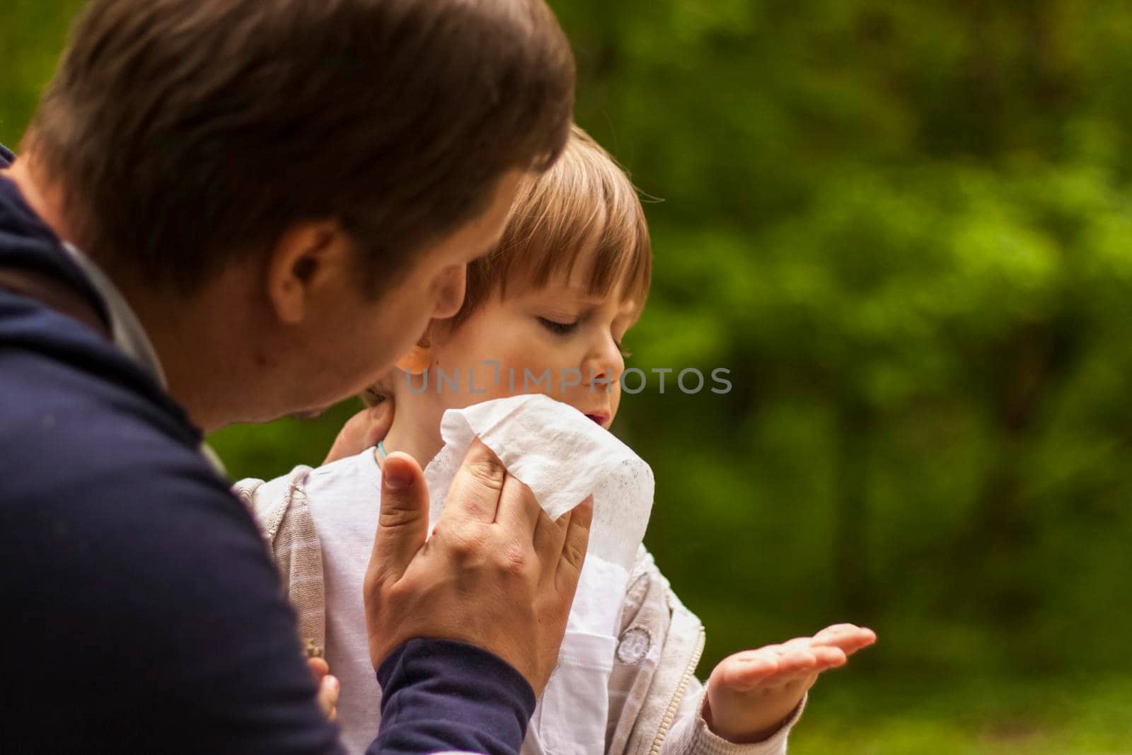 The father takes care of his little son. The father wiped the child's face with a napkin. Baby care, paternity, custody.