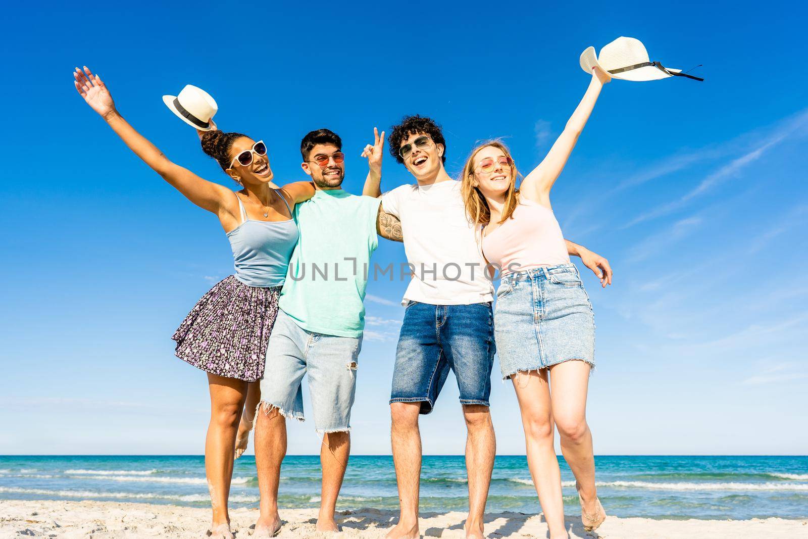 Group of multiracial young tourists posing for portrait photography in summer at tropical sea ocean resort with blue sky and crystal clear water. Happy millennial people on summer beach vacation by robbyfontanesi