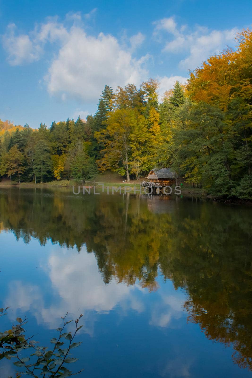 Lake and reflection in a lake showing forest and cabin. Lake is Trakoscan lake near castle Trakoscan in north-west Croatia.