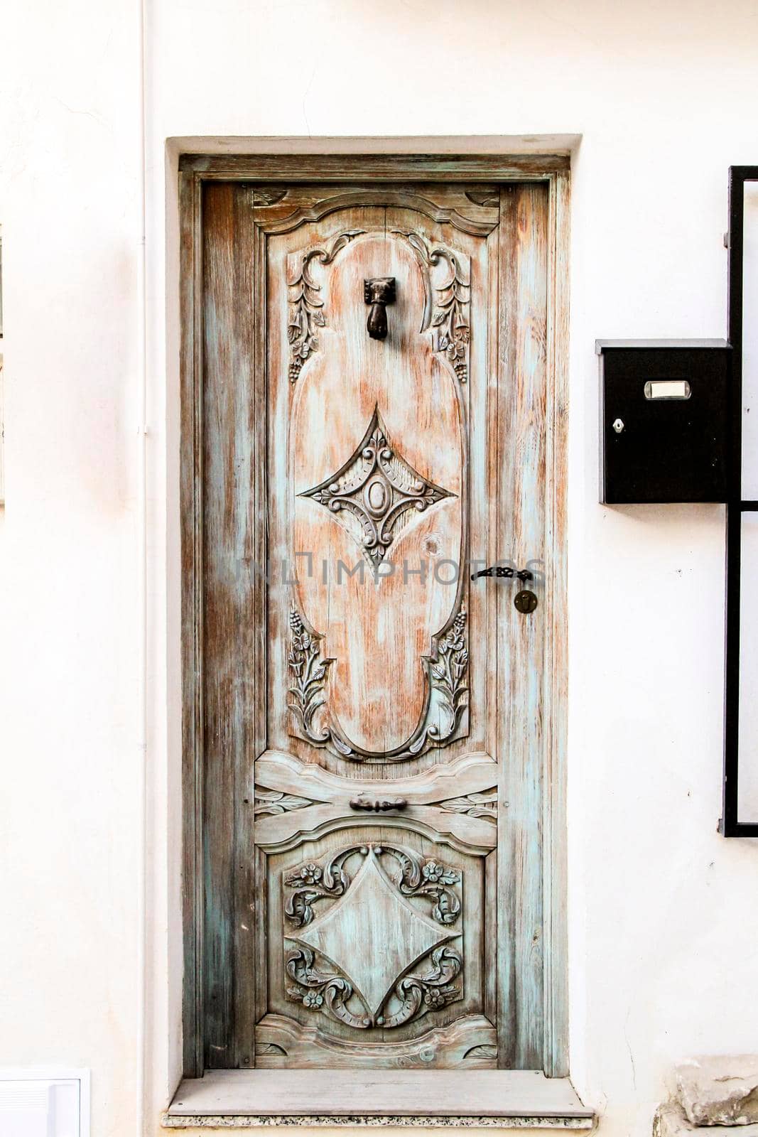 Blue wooden door with black metal knocker and whitewashed facade in Altea, Alicante, Spain.
