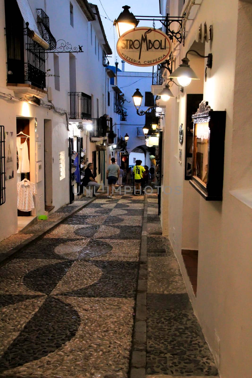 Altea, Alicante, Spain- June 12, 2021: People going shopping, walking and relaxing at night through the Narrow streets of Altea village, Alicante, Spain