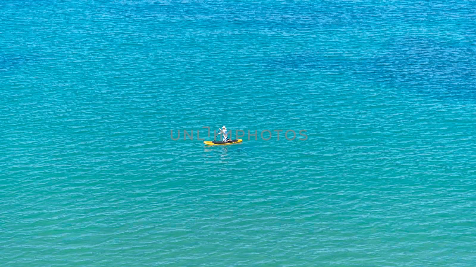 Seascape with a man on a sup board on the background of the water surface