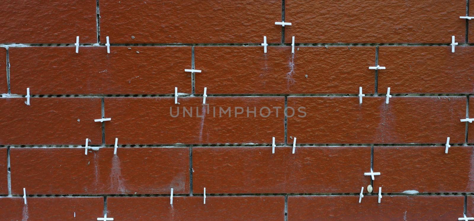 brown tiles in the process of laying. White auxiliary plastic crosses in the slots by ndanko