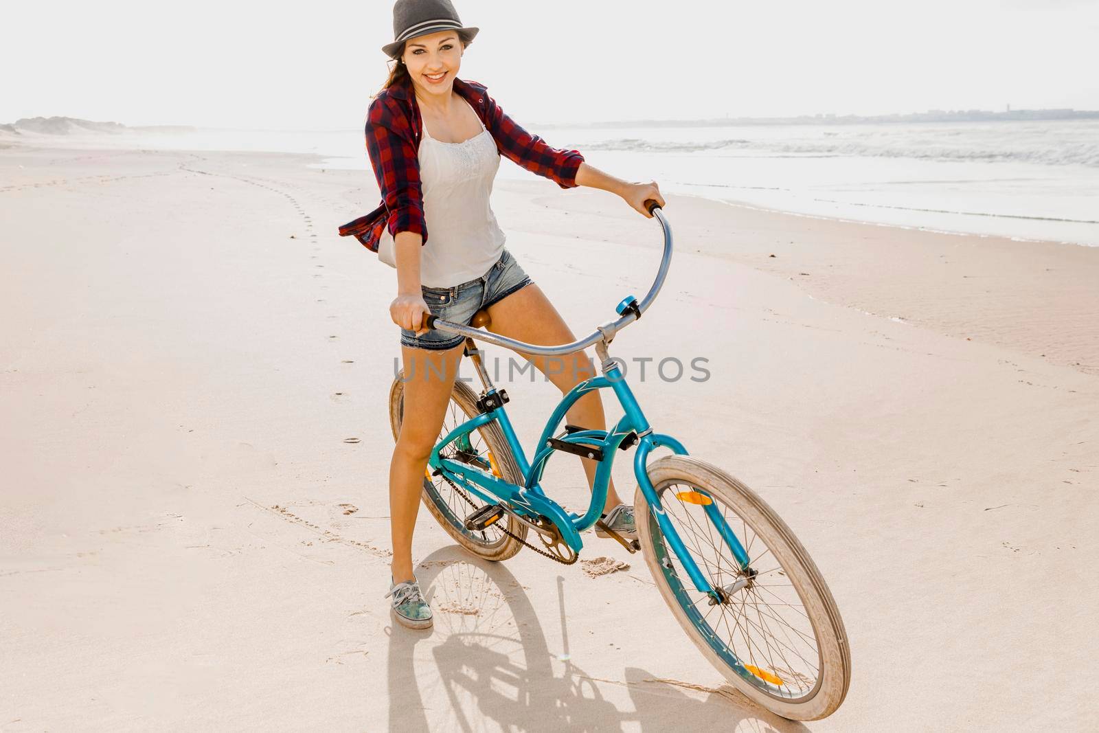 An attractive young woman riding her bicycle on the beach