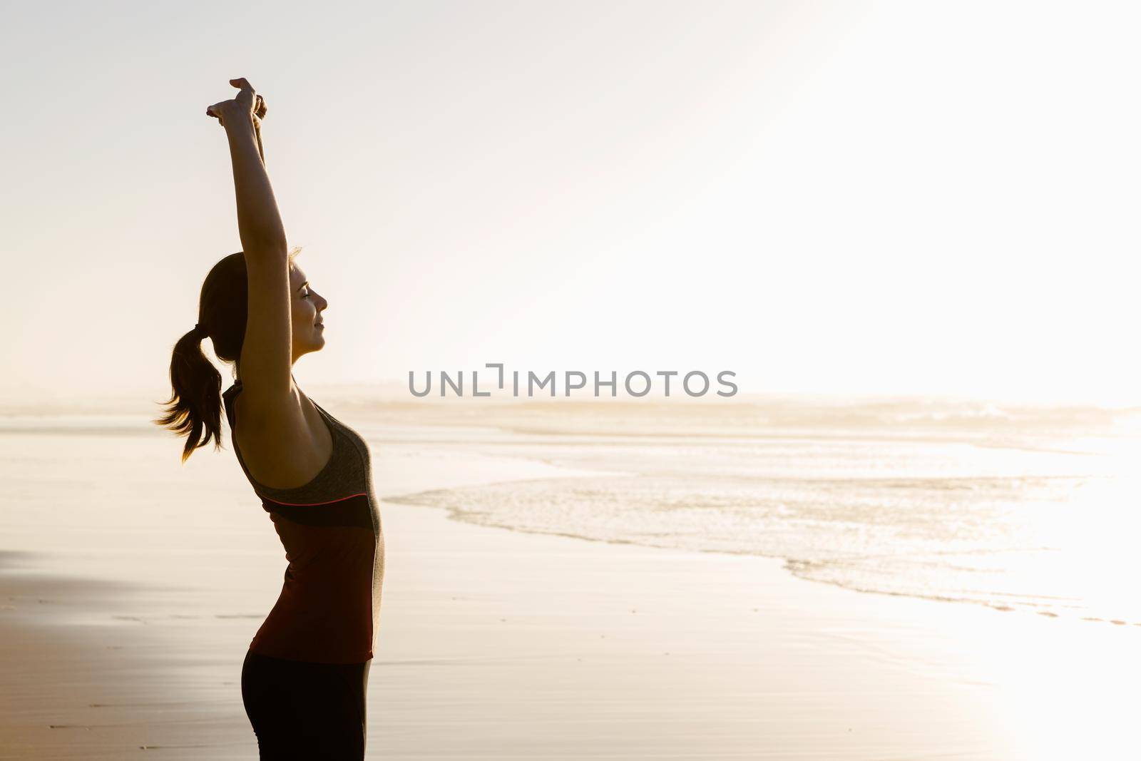 Shoot of a beautiful woman making stretching exercises in the beach