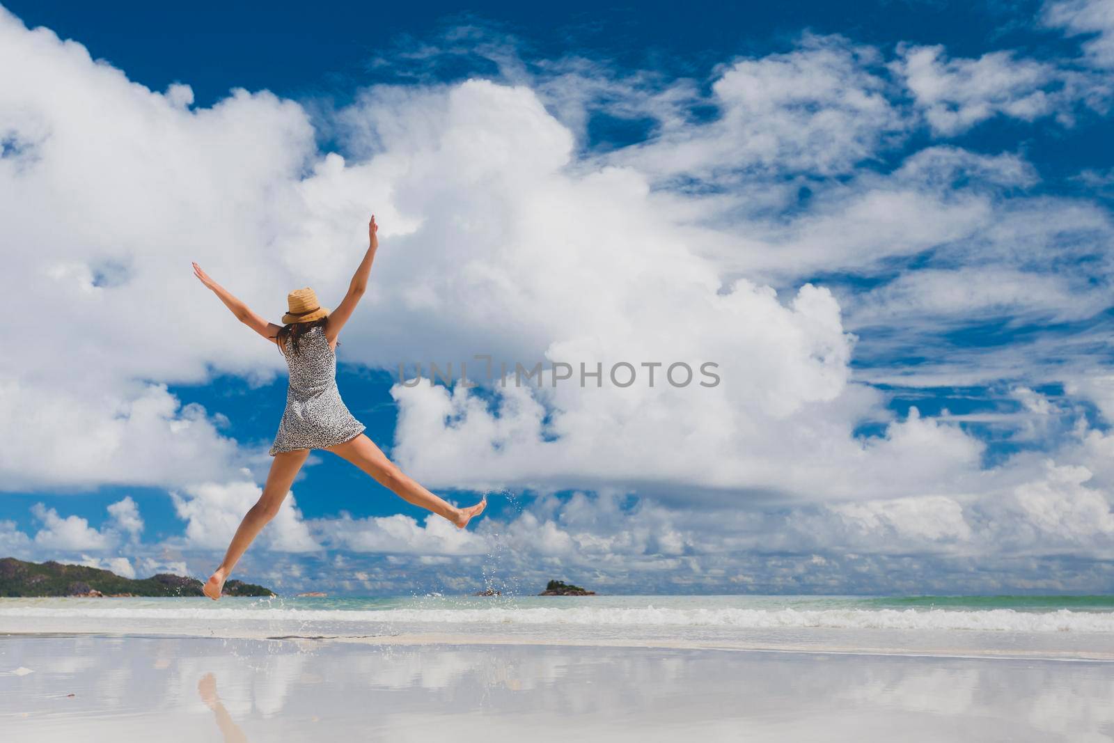 Beautiful woman jumping on the wonderful beach of Praslin, Seychelles