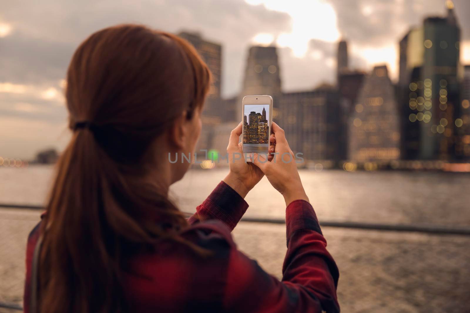 Woman taking a photo with a cell phone to the syline in Manhattan