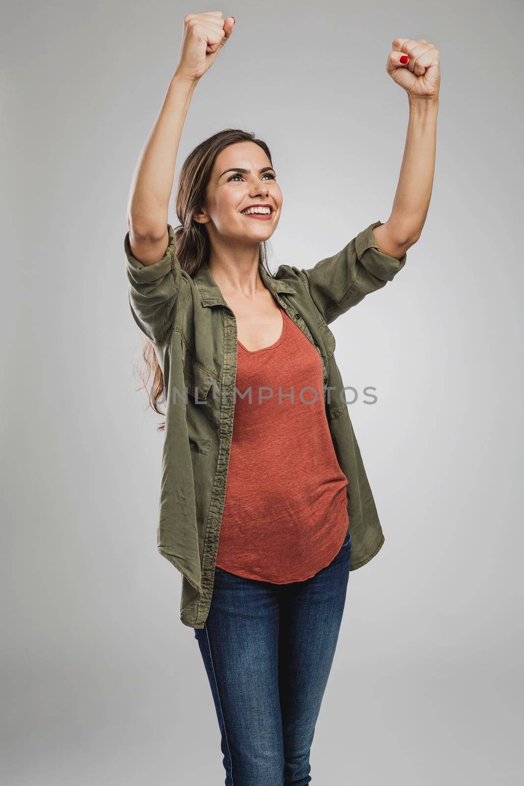 Beautiful and successful young woman with arms raised