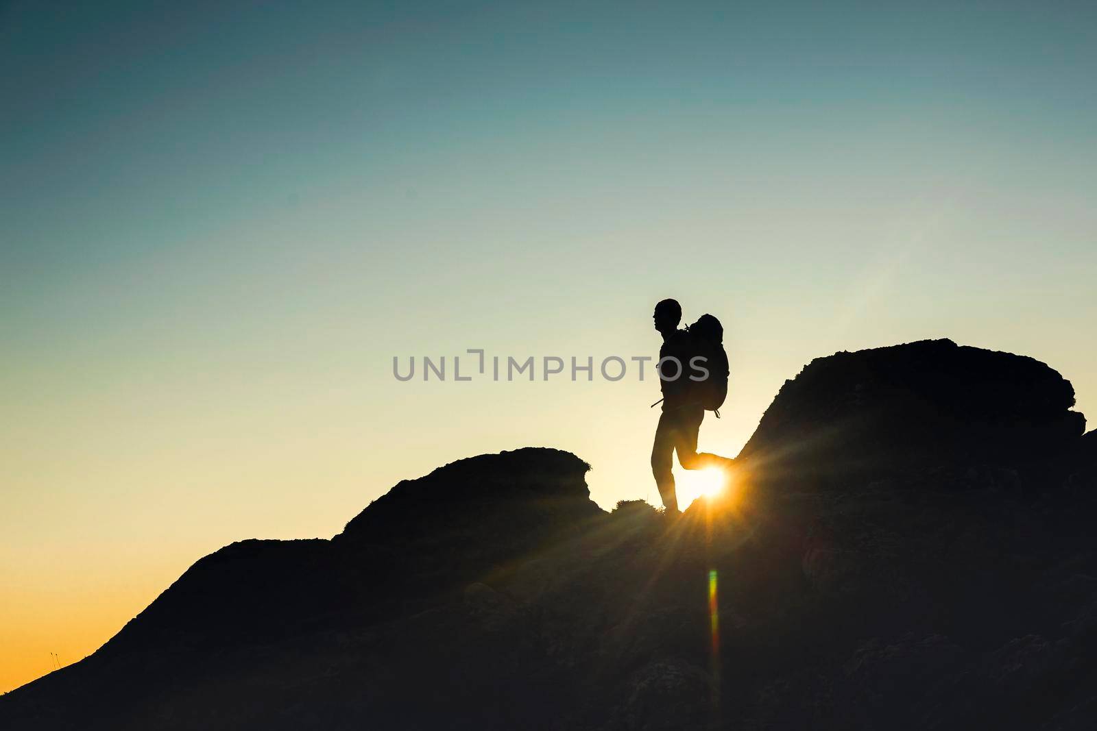 Shot of a man walking over the montains at sunset