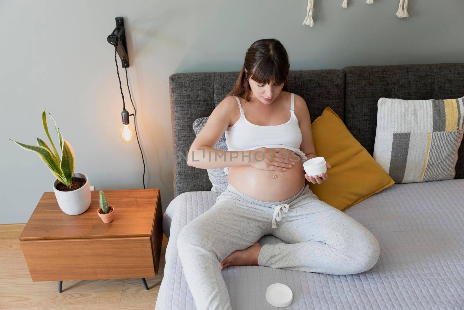 Pregnant woman applying stretch mark cream in her belly