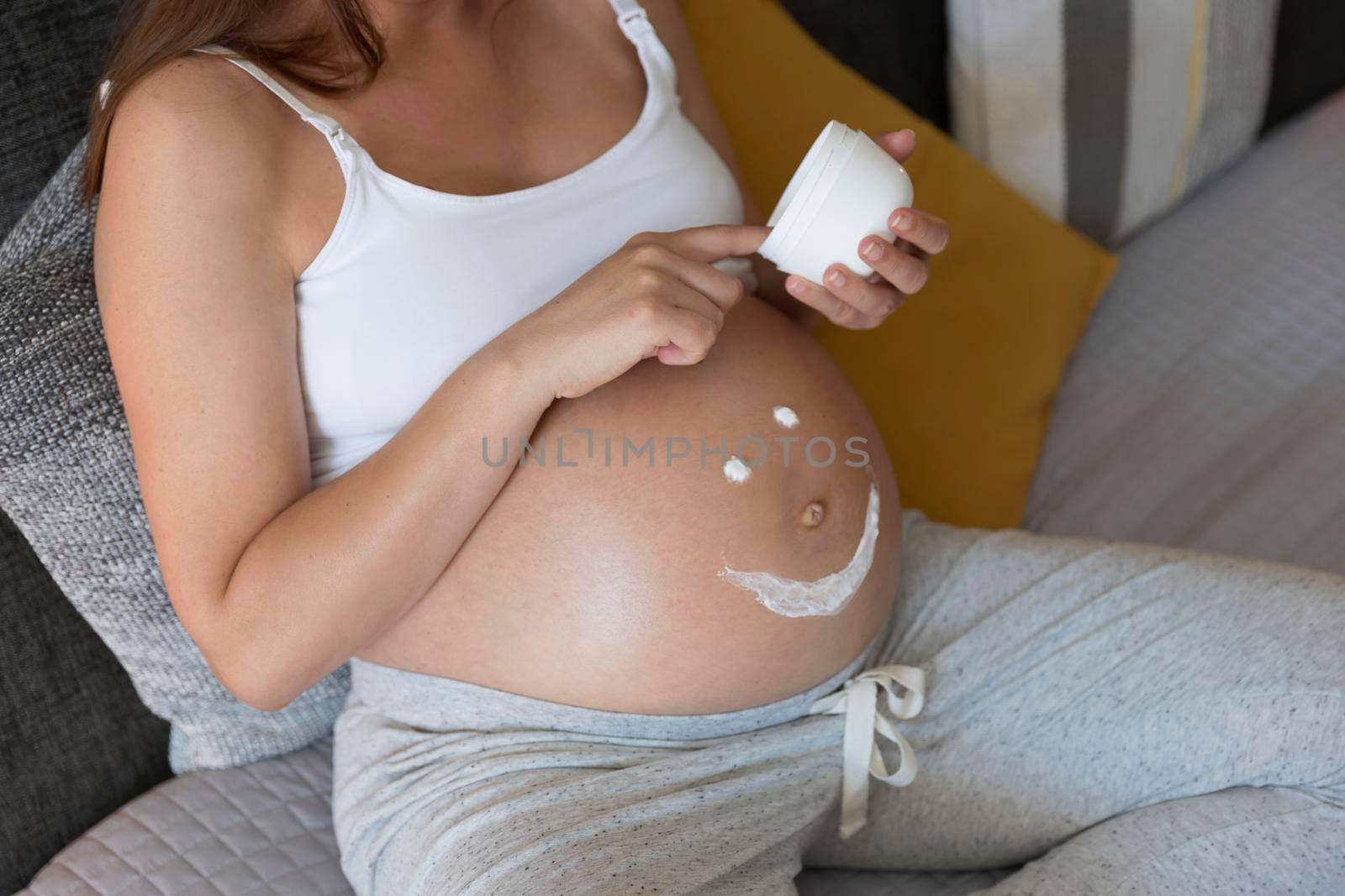 Pregnant woman applying stretch mark cream in her belly