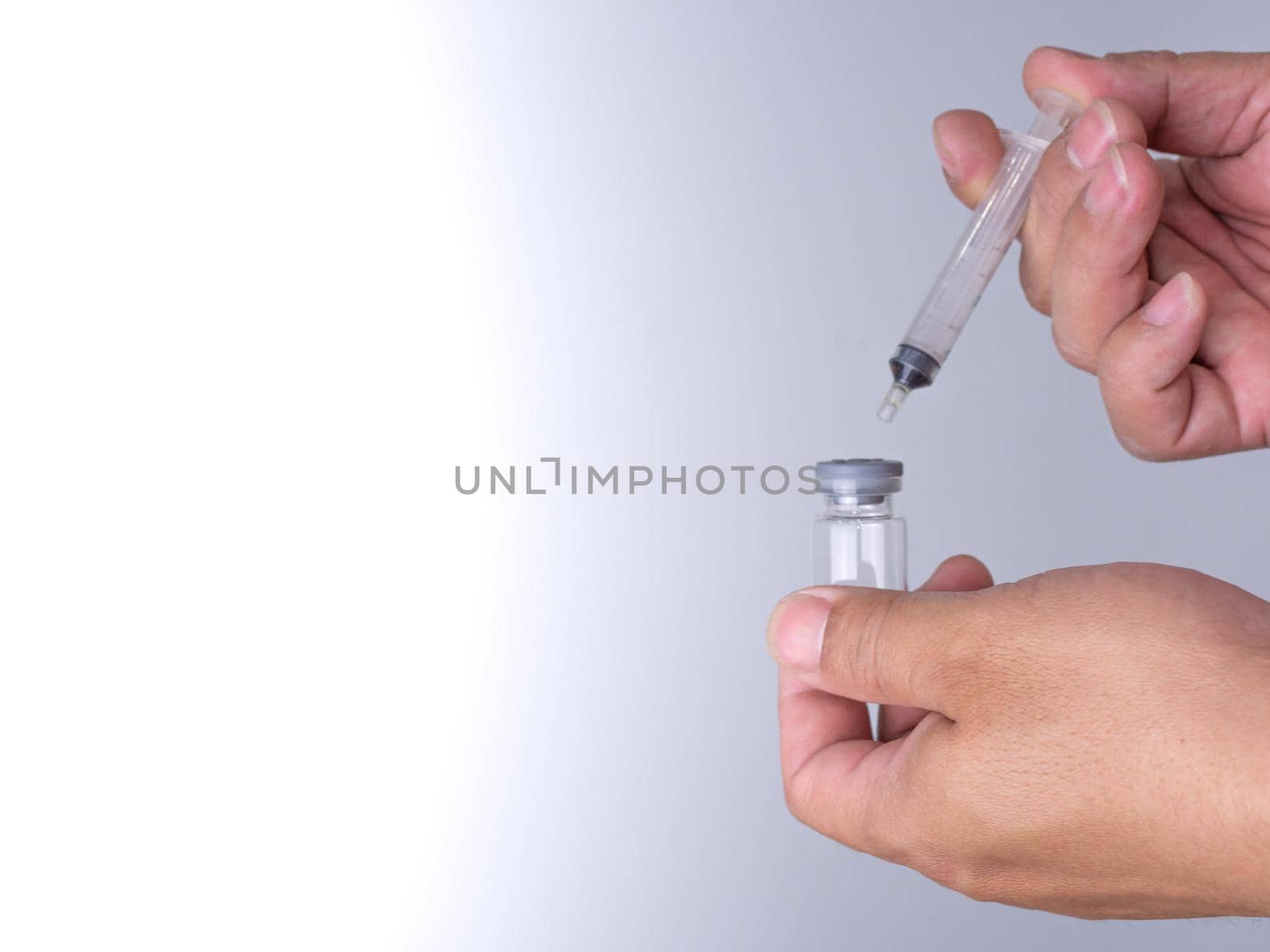 A man's hand is holding a bottle of vaccine and a sling for injection.