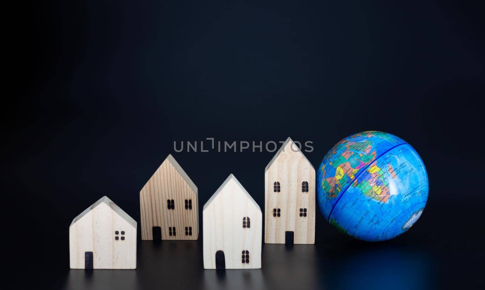 Model wooden houses and miniature globes Blank on a black background. Propose the concept of coexistence in the same world.