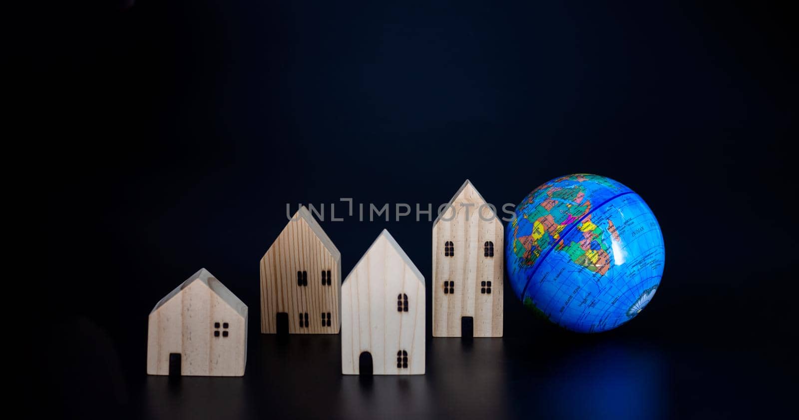 Model wooden houses and miniature globes Blank on a black background. Propose the concept of coexistence in the same world. by Unimages2527