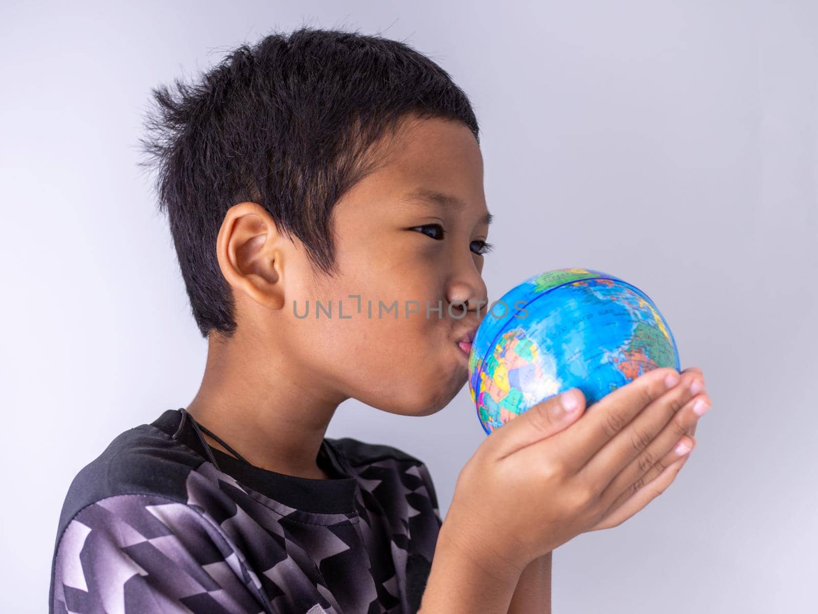 A boy hands the globe and kisses it on the globe. Show the power of the new generation to continue to develop our world.