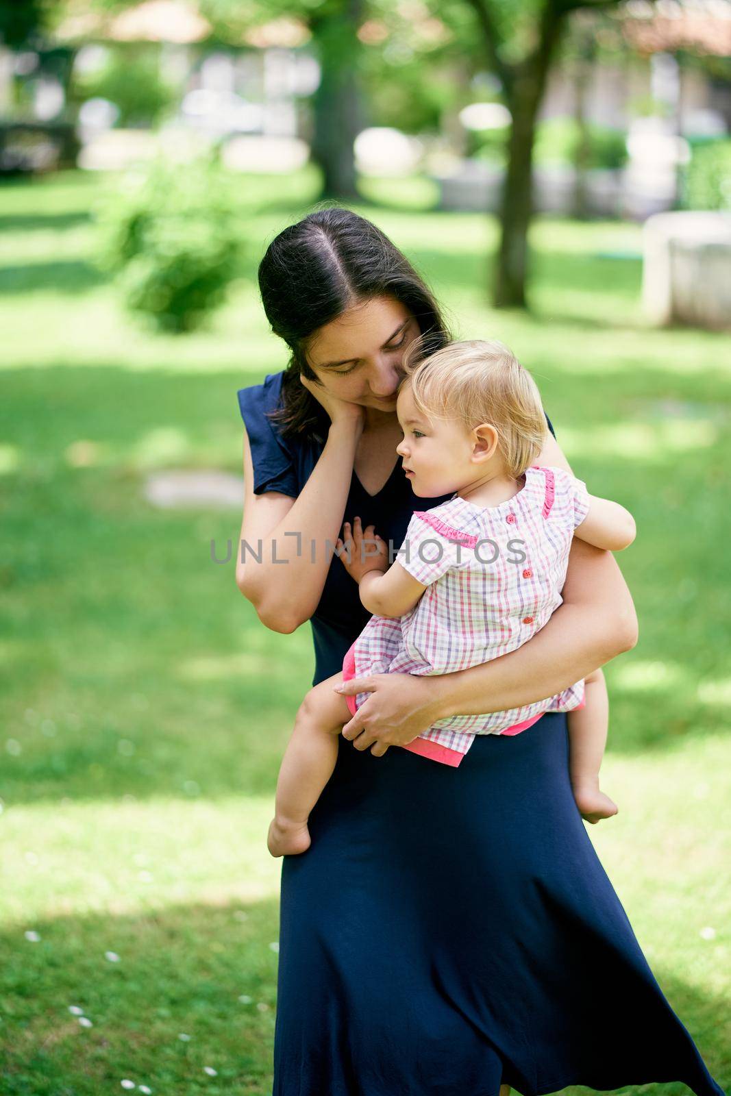 Mom holds a little girl in her arms, leaning over her. High quality photo
