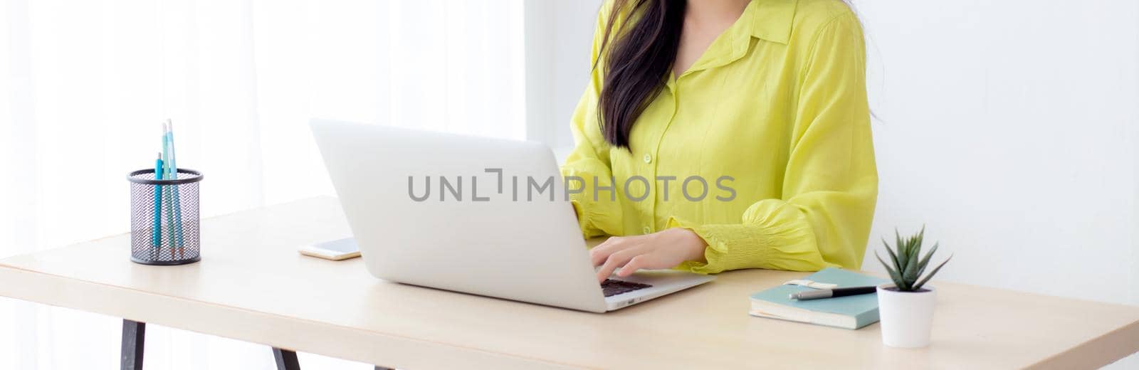 Young asian businesswoman working on laptop computer on desk at home office, freelance looking and typing on notebook on table, lifestyle of woman studying online, business and education concept. by nnudoo