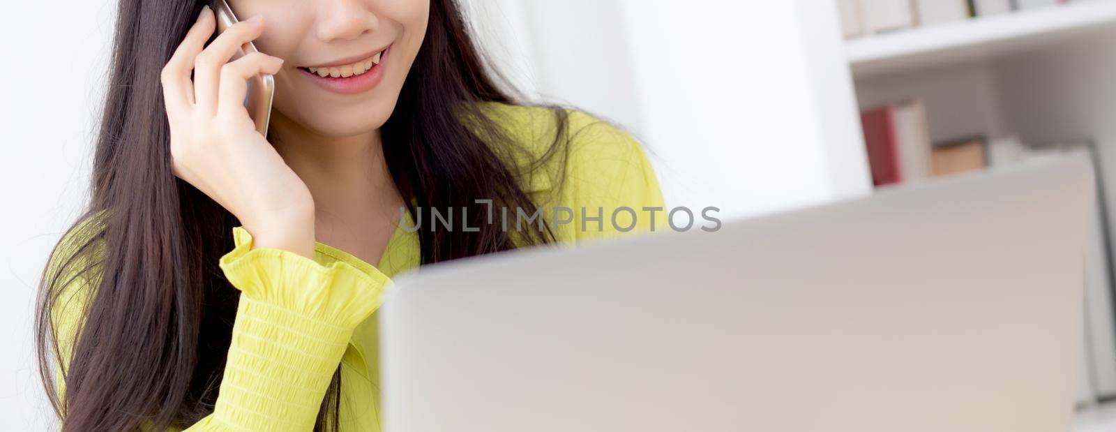 Young asian business woman working form home office and call phone for success at home, businesswoman using laptop computer on desk, female talking smartphone at workplace, communication concept. by nnudoo