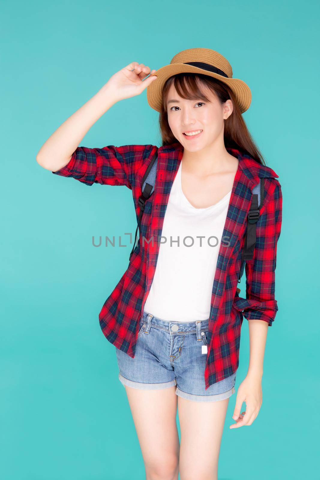 Beautiful portrait young asian woman holding hat smile expression cheerful and enjoy travel summer trip holiday in vacation isolated blue background, tourist happy asia girl confident and excited.