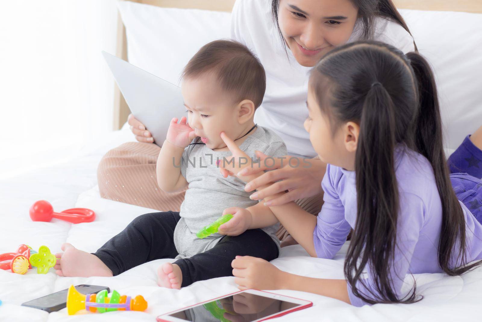 Young asian mother and baby girl lying and playing on the bed together, mom and daughter, family of emotion and expression with happy, parent and newborn relax and positive, emotion and expression.