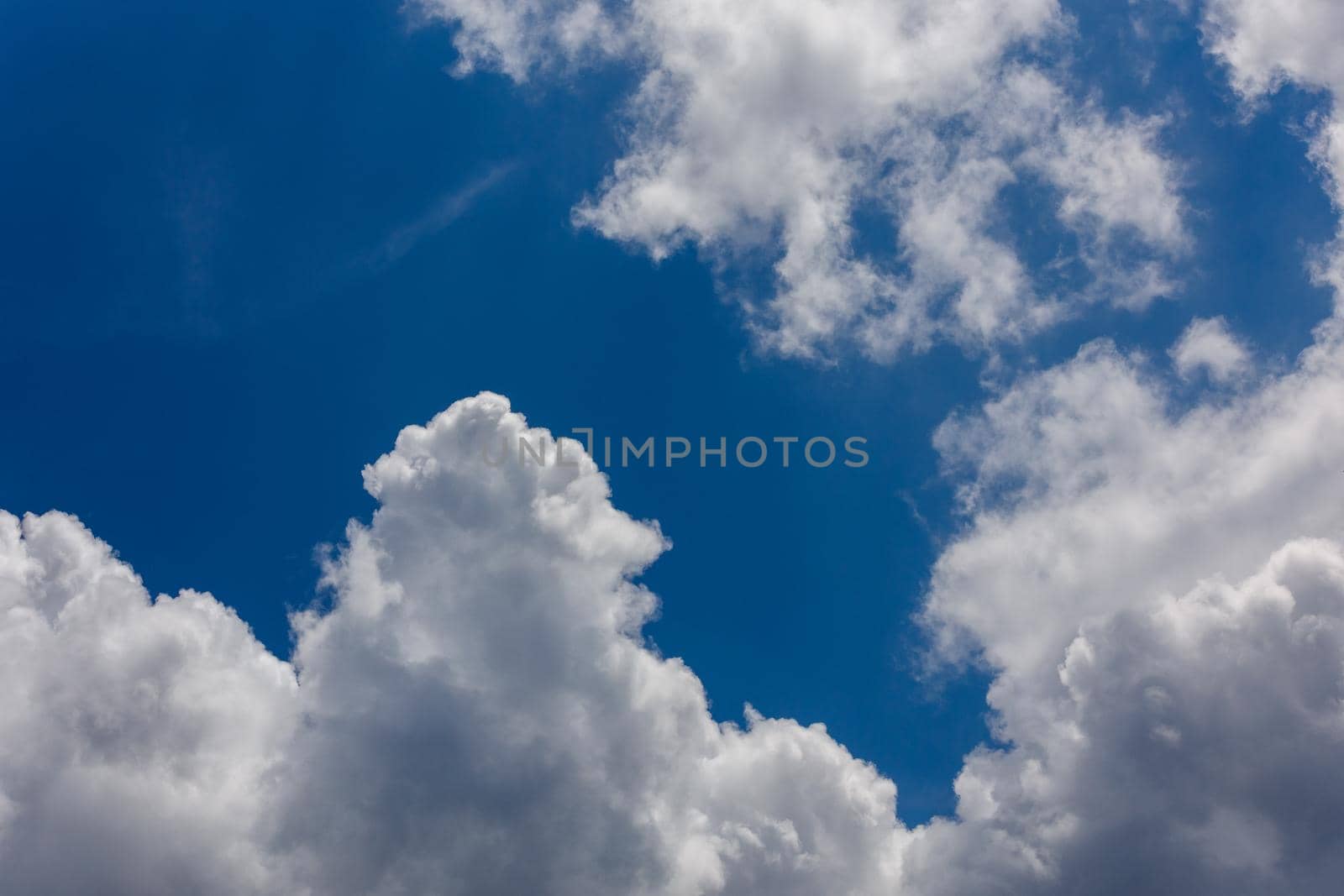 white c cumulus clouds on blue sky background telephoto view