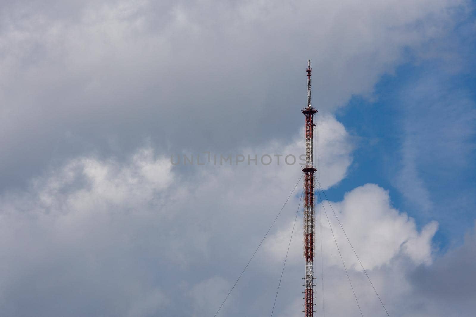 tall metal frame television tower on cloudy sky daylight background.