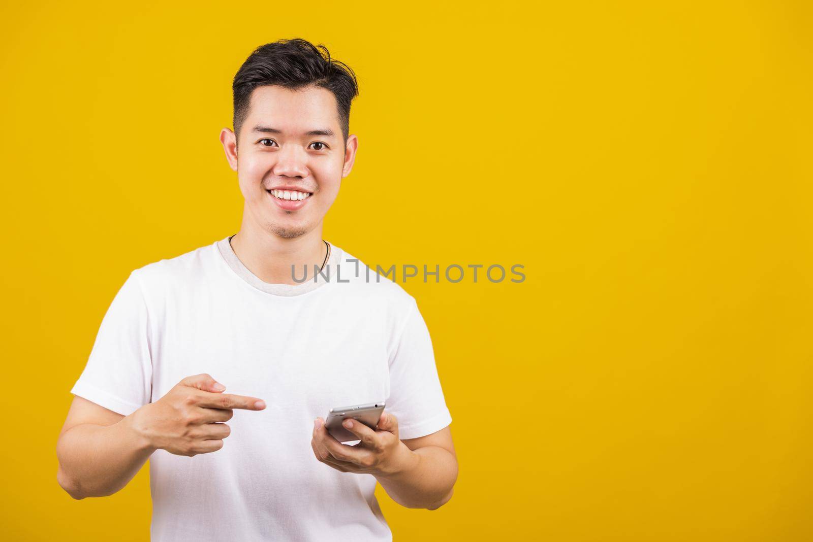 man smiling positive holding smartphone blank screen and pointing finger to mobile phone by Sorapop