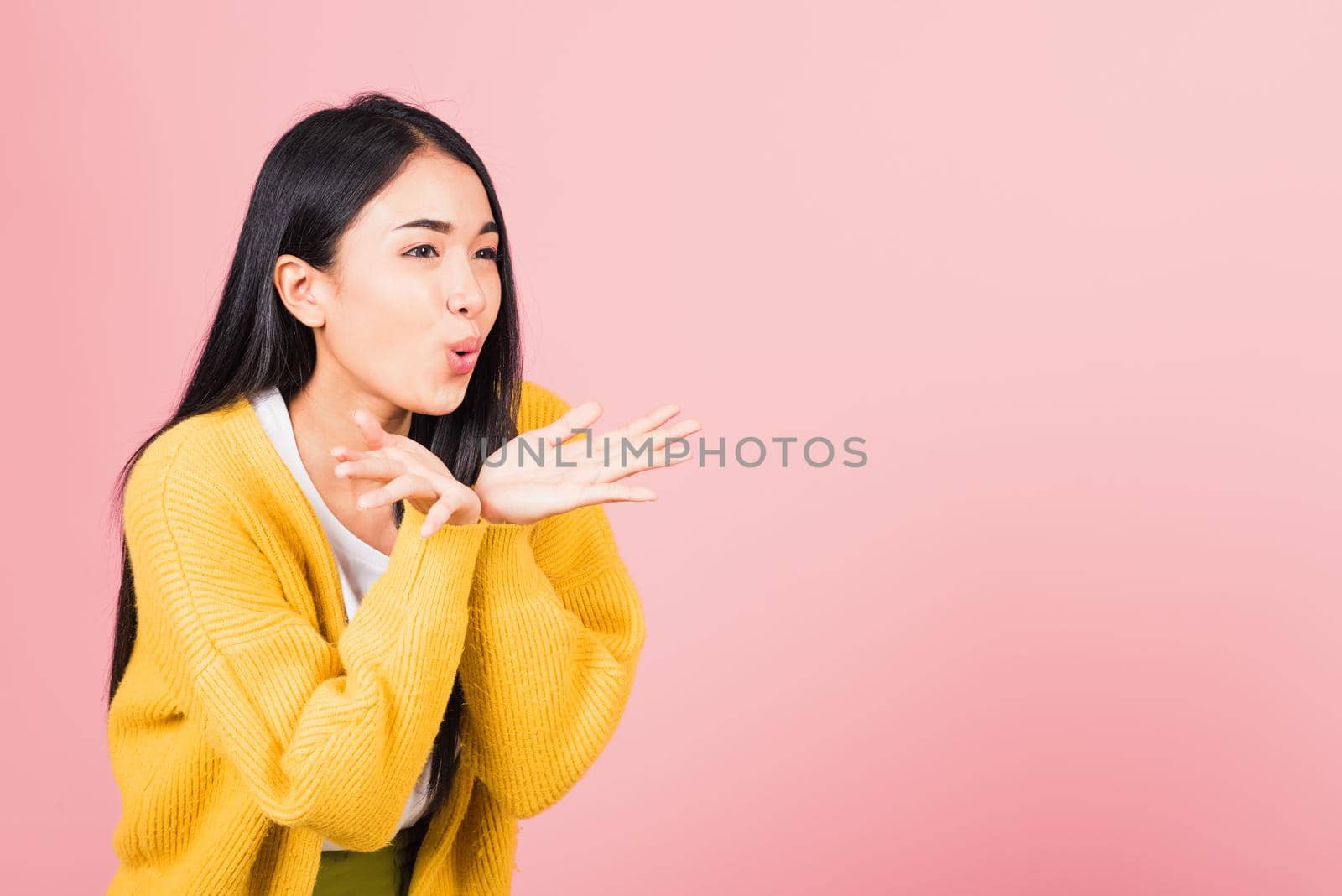 Asian happy portrait beautiful cute young woman teen standing blowing kiss air something on palm hands expresses her love looking to side away studio shot isolated on pink background with copy space