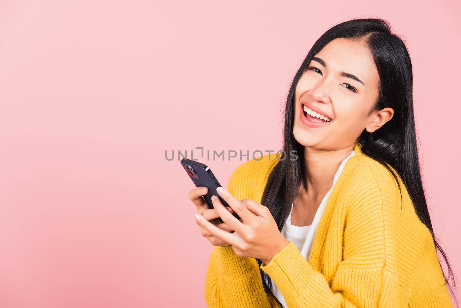 beautiful cute young woman excited laughing holding mobile phone by Sorapop