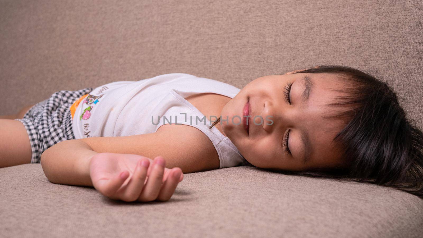 Cute little girl sleeping on sofa in the living room at home.