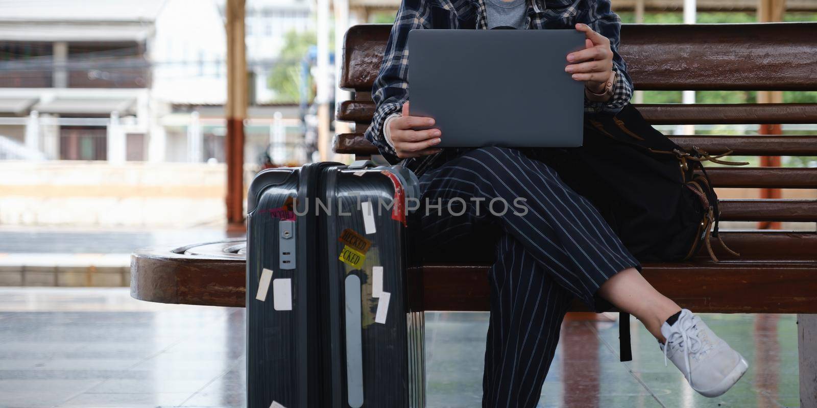 Image of Young freelance working at train station before travel and social distancing symbol on bench. work and travel concept