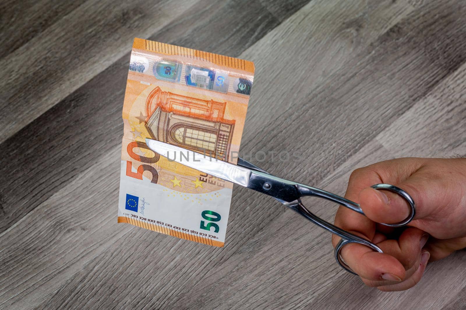 man cutting 50 euro banknotes with scissors by carfedeph