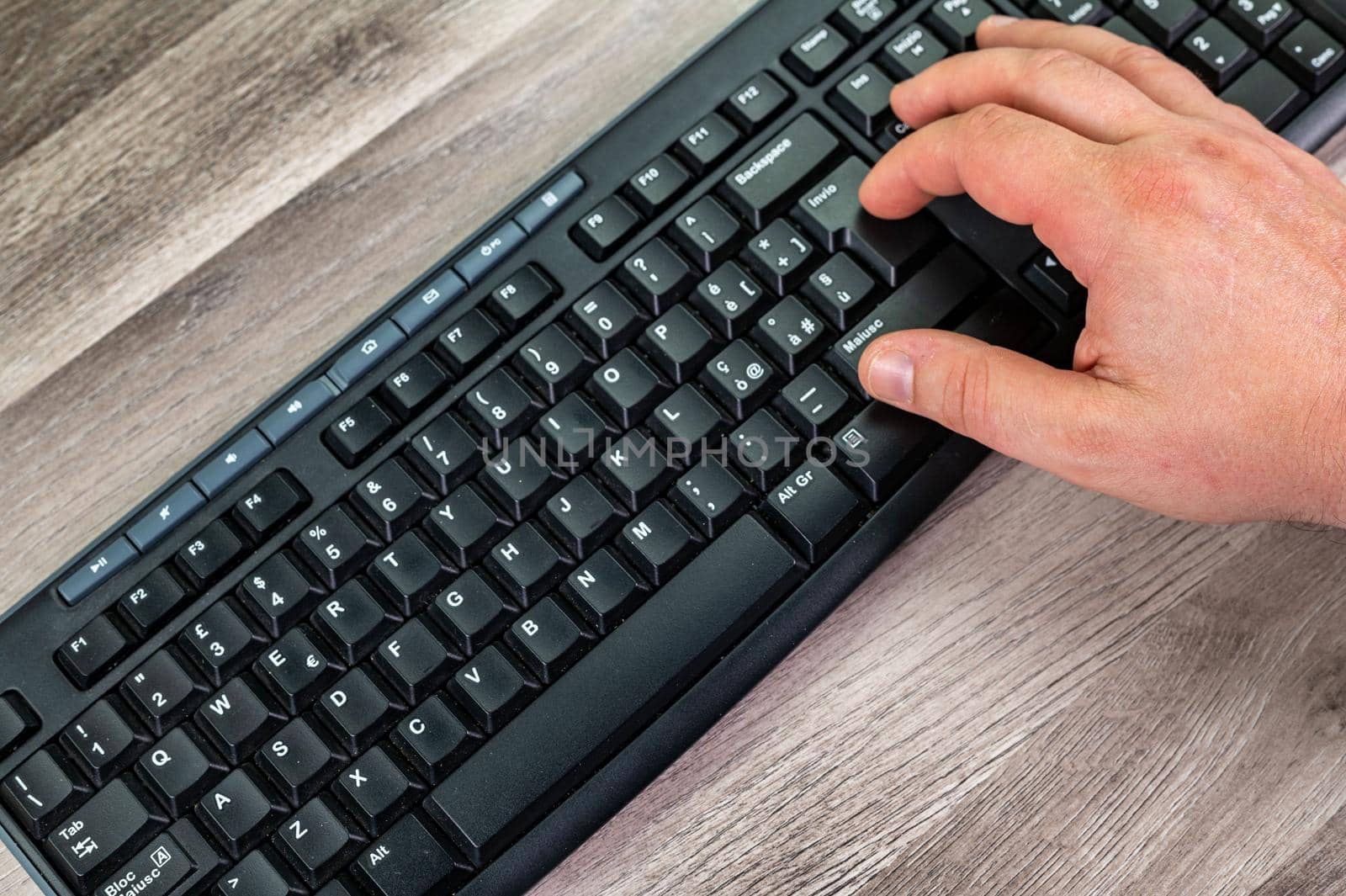 hands of a man typing on the keyboard pcsu wooden table