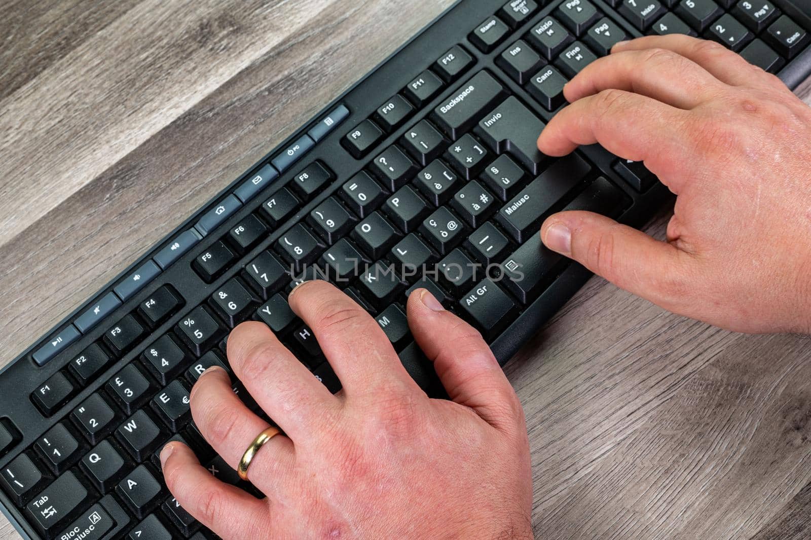 hands of a man typing on the keyboard pcsu wooden table